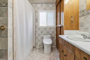 Full bath with a shower stall, vanity, and tile walls