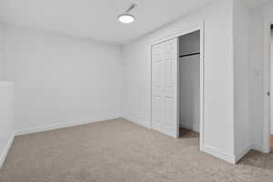 Unfurnished bedroom with light carpet and a closet