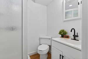 Full bathroom with vanity, a stall shower, a textured wall, and wood finished floors