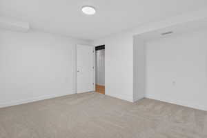 Unfurnished bedroom with light carpet and baseboards