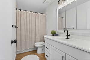 Bathroom featuring vanity, light wood finished floors, a shower with shower curtain, a textured wall, and a textured ceiling