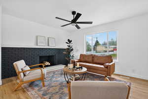 Living area with wood finished floors, a fireplace, and ceiling fan
