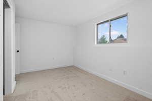 Empty room featuring light colored carpet and baseboards