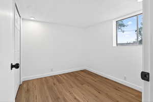 Unfurnished room with wood finished floors, recessed lighting, and a textured ceiling