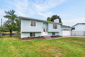Bi-level home with a chimney, a garage, and concrete driveway