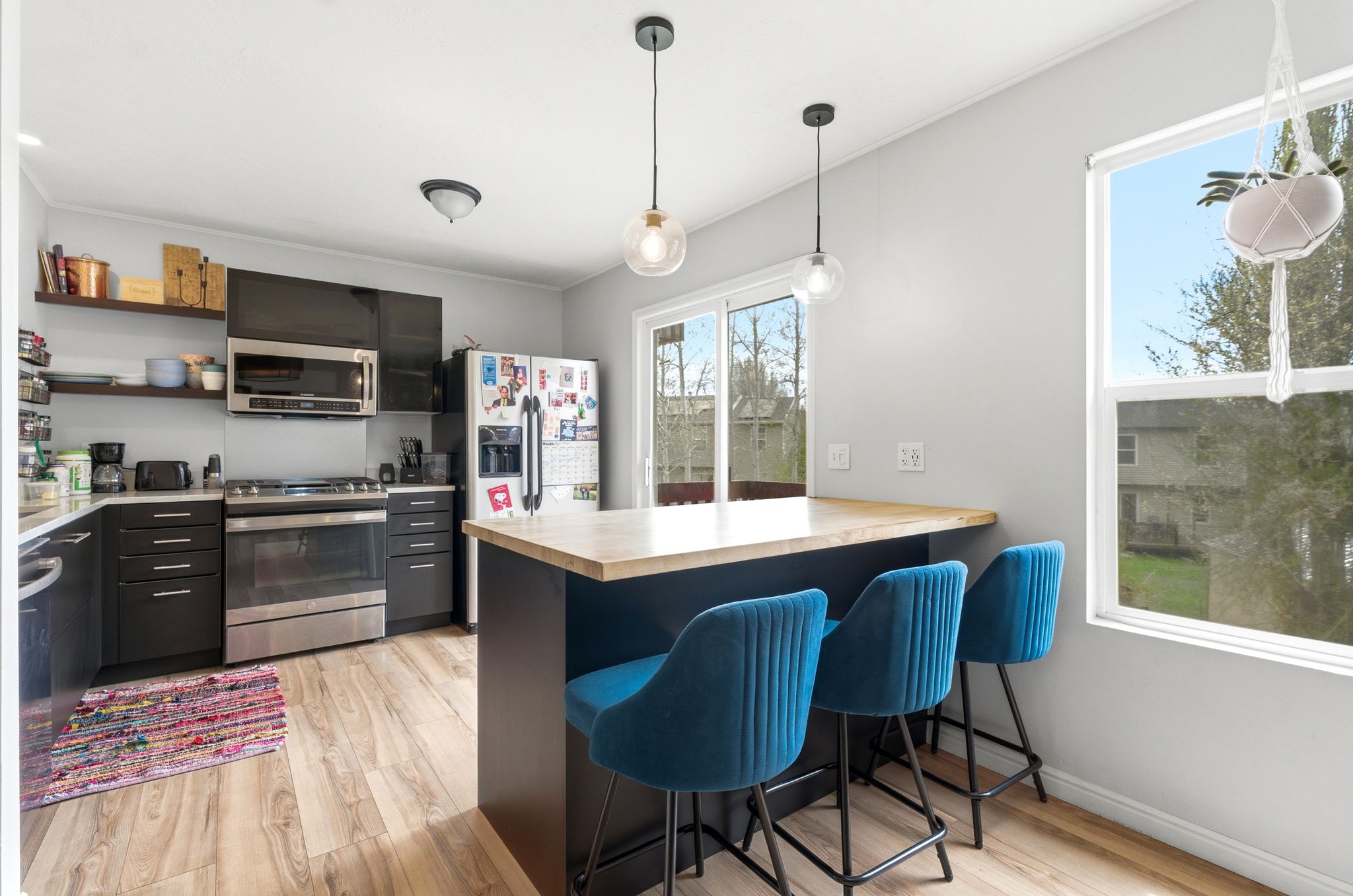 Kitchen featuring a kitchen breakfast bar, stainless steel appliances, light wood-style flooring, and decorative light fixtures