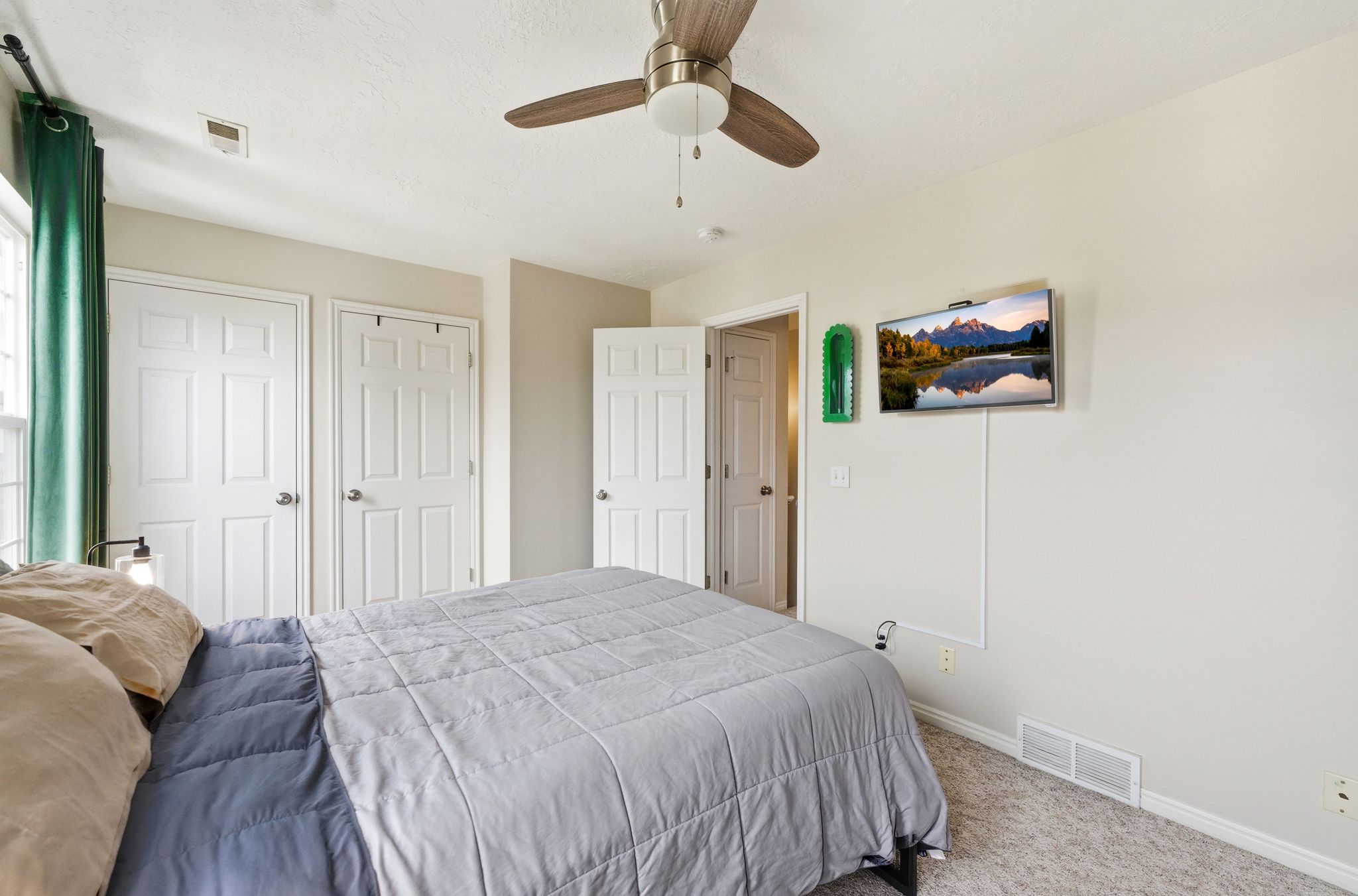 Carpeted bedroom with two closets and ceiling fan
