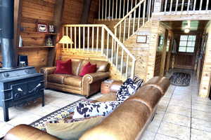 Living area with wooden walls, a wood stove, and tile patterned floors