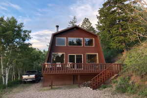 Back of property featuring a deck and view of wooded area