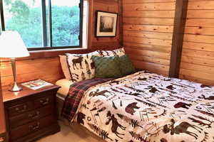 Carpeted bedroom featuring wooden walls