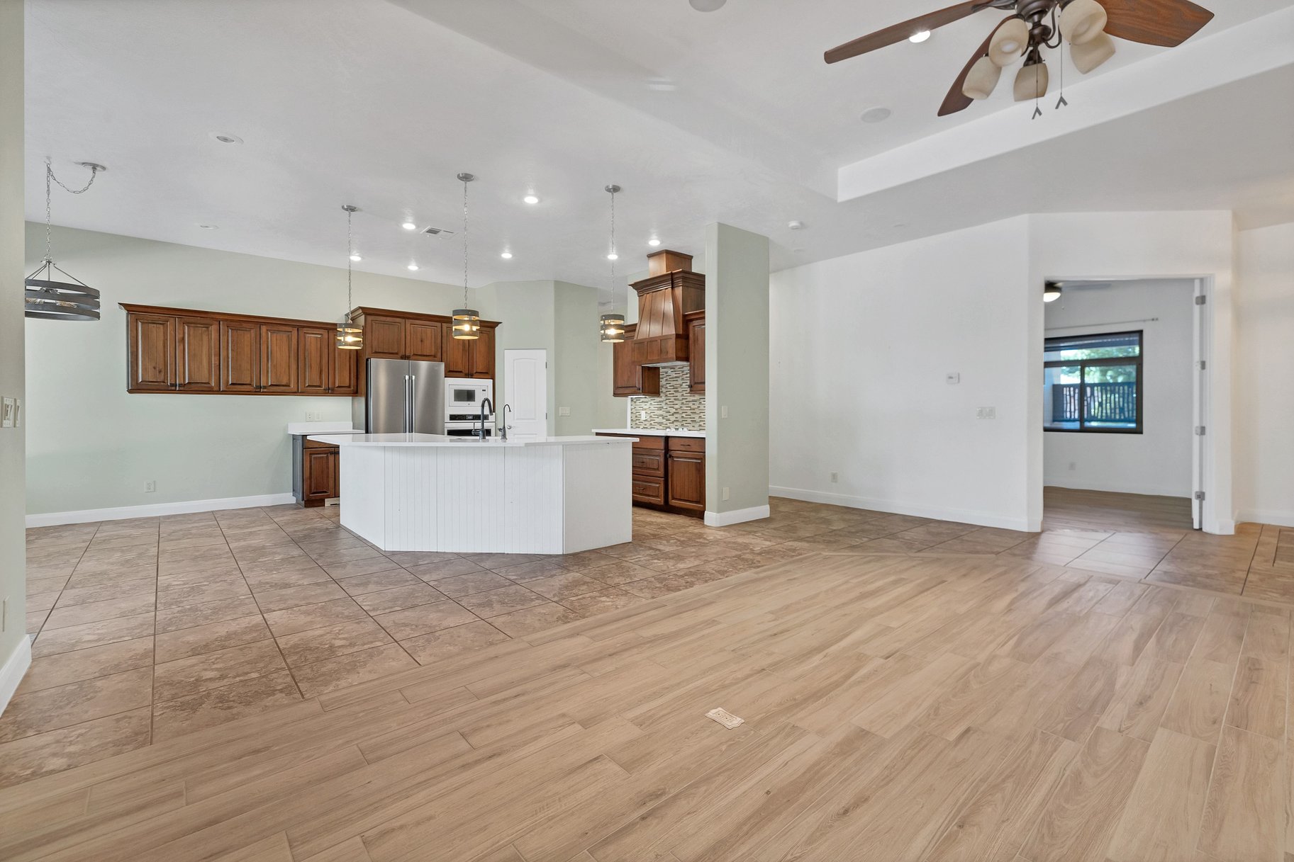 Kitchen featuring open floor plan, light countertops, a center island with sink, wood finish cabinetry, and light wood-style floors