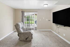 Living area featuring light colored carpet and a textured ceiling