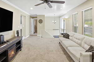 Living room with light colored carpet, ceiling fan, crown molding.