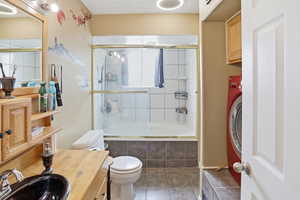 Bathroom with washer / dryer, tiled shower / bath combo, and vanity