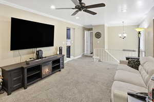 Living area with light carpet, ceiling fan, ornamental molding