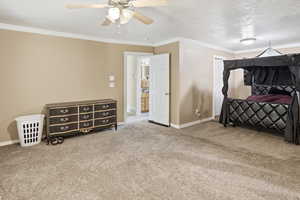Bedroom featuring a textured ceiling, crown molding, carpet floors, and ceiling fan