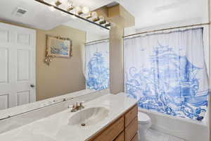 Full bathroom with vanity, shower / tub combo, and a textured ceiling