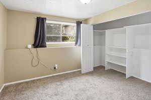 Bedroom with a closet, light carpet, and a textured ceiling