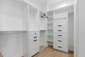 HER walk in closet with light wood-style flooring