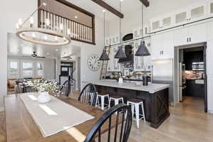 Dining area featuring light wood-type flooring, a ceiling fan, a high ceiling, and hanging lights