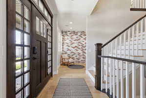 Entrance foyer featuring light wood-style floors and brick wall