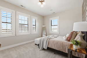 Bedroom with light carpet and a chandelier