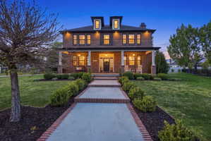 View of front facade with covered porch, a front lawn, brick siding, and a chimney