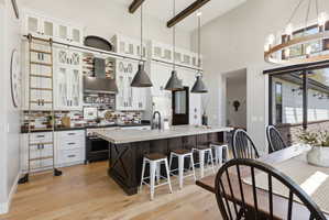 Kitchen featuring two tone cabinetry, a breakfast bar, light wood-type flooring, high end appliances, and glass fronted cabinets