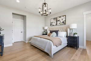 Bedroom with light wood-style flooring and suspended lighting