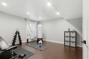 Workout room with dark wood-style floors and recessed lighting