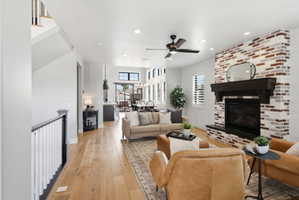 Living room featuring light wood-style floors, a brick fireplace, ceiling fan, and recessed lighting