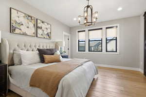 Bedroom featuring light wood-style floors, a chandelier, and a barn door