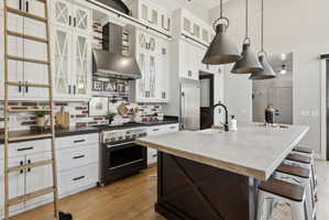 Kitchen featuring a breakfast bar area, light wood-style flooring, high end appliances, dual tone cabinetry, and decorative light fixtures