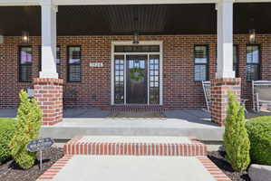 Entrance to property with covered porch and brick siding