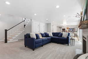 Living room with light carpet, a fireplace with flush hearth, and a chandelier