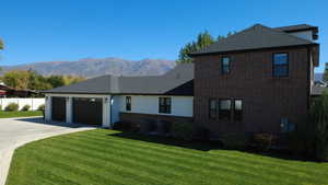 View of front of home with brick siding, a garage, a mountain view, and concrete driveway