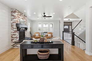 Living area with a brick fireplace, light wood finished floors, ceiling fan, and recessed lighting