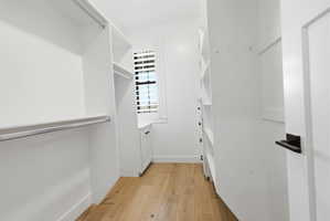 HIS walk in closet featuring light wood-style flooring