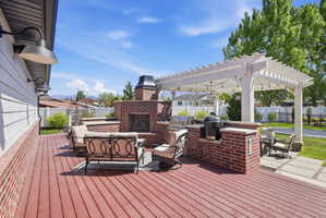 Wooden terrace featuring an outdoor kitchen, an outdoor brick fireplace, and outdoor lounge area