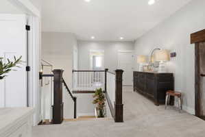 Hallway with light carpet, an upstairs landing, and recessed lighting