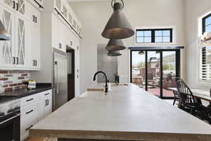 Kitchen with glass fronted cabinets, white cabinetry, premium appliances, a large island, and a high ceiling