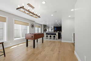 Game room with light wood-style flooring and recessed lighting