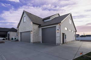 View of side of property featuring stone siding and driveway