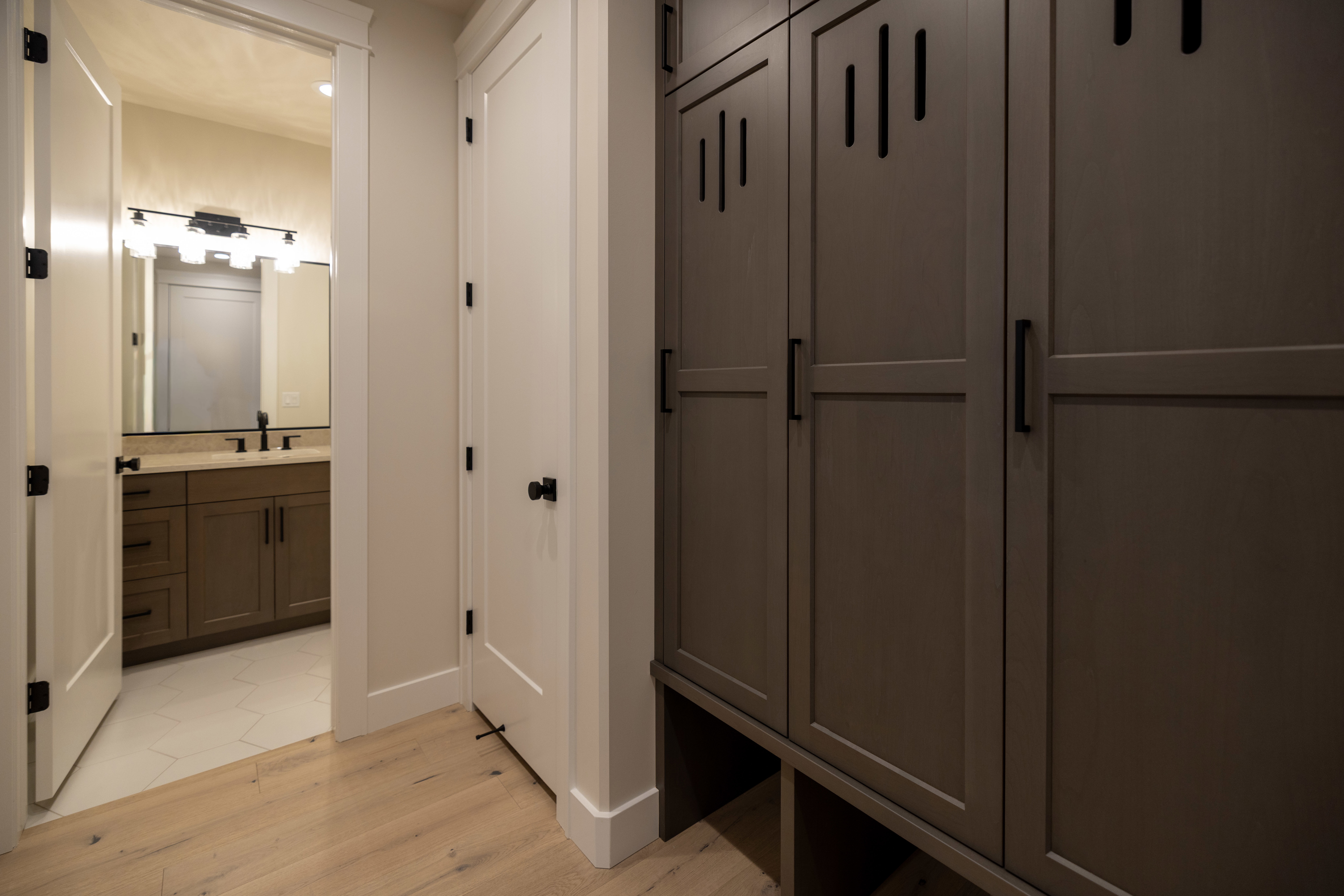 Mudroom with light wood-style tile flooring and half bathroom