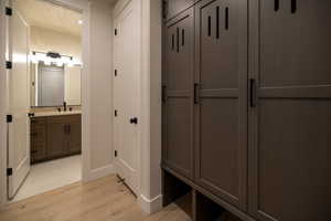 Mudroom with light wood-style tile flooring and half bathroom