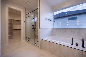 Master Bathroom featuring a dual shower head shower, a seperate bath, and a walk in closet