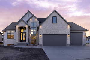 View of front of house featuring stone and stucco, driveway, roof with asphalt shingles, and a garage