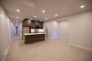 Kitchen with recessed lighting, a kitchen island with sink, light wood-type tile flooring, and stainless steel appliances
