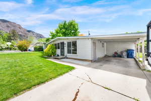 View of front of property with a front lawn, concrete driveway, and an attached carport