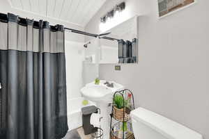 Bathroom with toilet and shower / bath combination with curtain